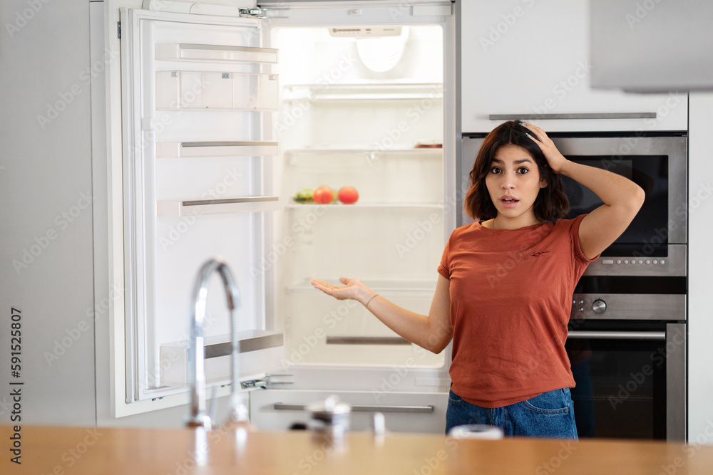 Shocked Young Arab Woman Near Empty Fridge With No Food At Home Shocked Young Arab Woman Near Empty Fridge With No Food At Home