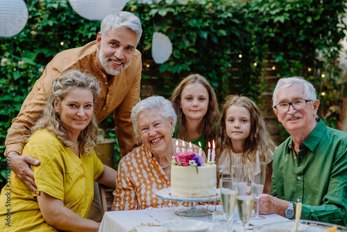 Multi-generation family on outdoor summer garden party, celebrating birthday