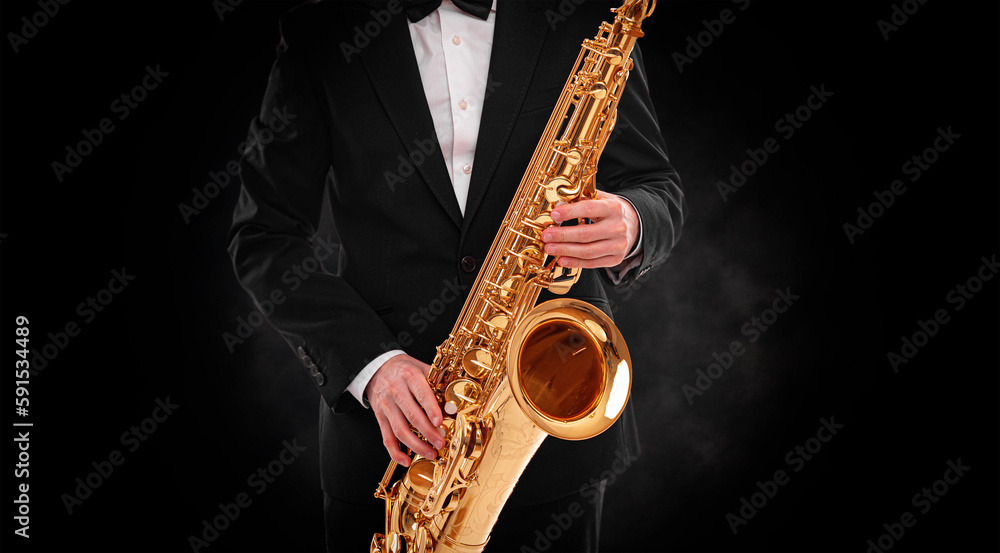 Naklejka premium Saxophonist on a black background close-up.