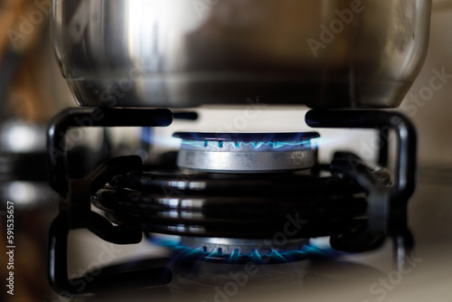 Metalowy garnek na kuchni gazowej z pal  cym si   palnikiem blekitnego paliwa