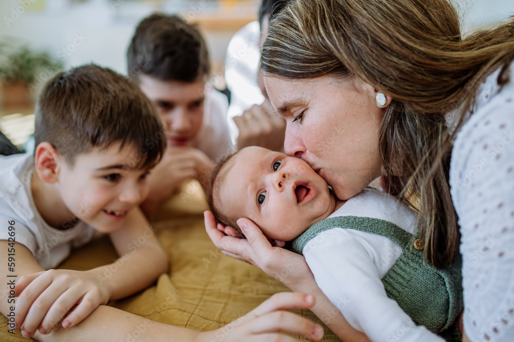 Portrait of mother kissing her newborn baby, other siblings stoking him. Portrait of mother kissing her newborn baby, other siblings stoking him.