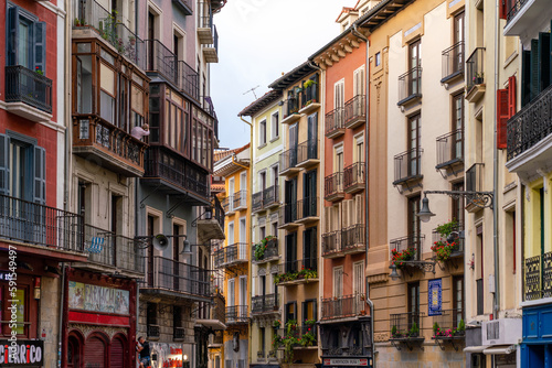 PAMPLONA, SPAIN - JULY 04, 2022: Pamplona, Navarra, SPAIN. The beautiful streets of the city of Pamplona. Beautifully coloured buildings with flowers of different colours, hanging from the balconies.