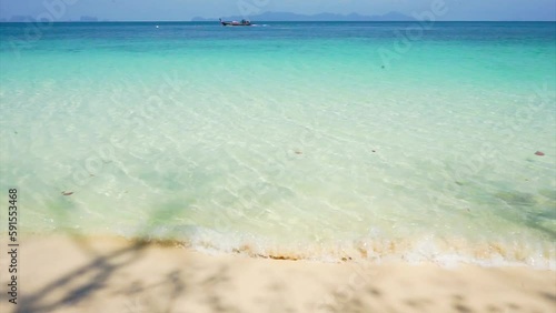 Aerial view of the sand with the sea surfing on the sea and the moving long tail boat in background.