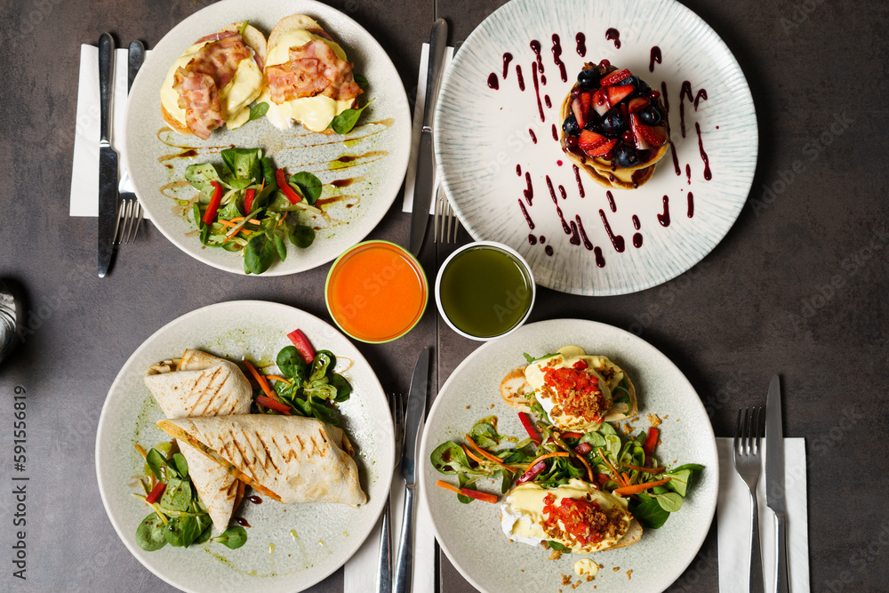 Brunch with four plates of meals - egg toast, burrito, american pancake and juices Brunch with four plates of meals - egg toast, burrito, american pancake and juices