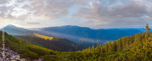 Last sun rays in evening sky with clouds above Syniak mountain. Summer sunset view from Homiak mountain  Gorgany  Carpathian  Ukraine.