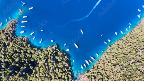 Aerial view of sailboats and swimmers enjoying the beautiful Kleopatra Hamamı Cove, located between Göcek and Dalaman, Turkey, known for its crystal-clear waters and ancient ruins. photo