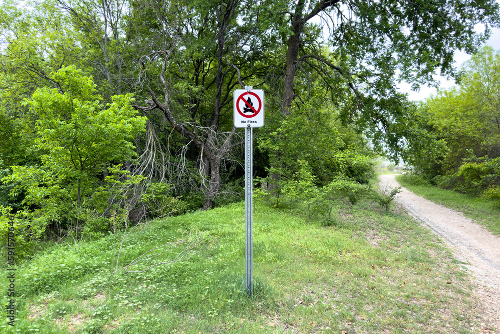 Naklejka premium No fire sign in green garden or park, warning about danger, information about fire prohibition, attention, no fire inscription on whiteboard in forest.