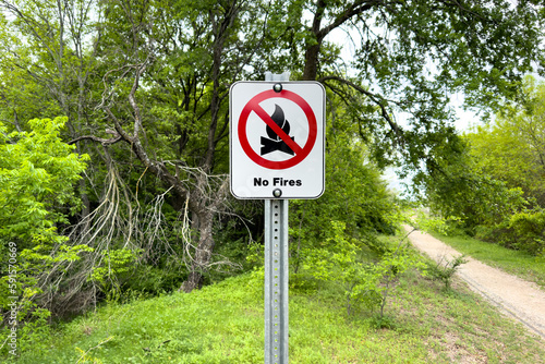 Billede på lærred No fire sign in green garden or park, warning about danger, information about fire prohibition, attention, no fire inscription on whiteboard in forest