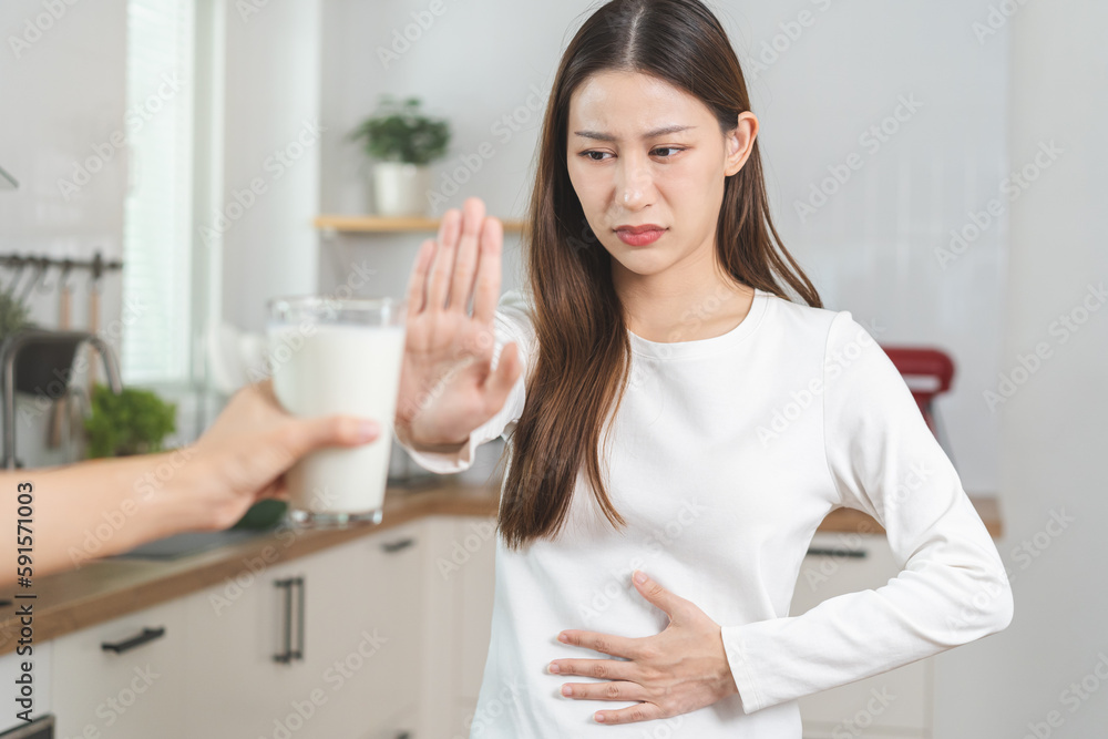 Allergy asian young woman, girl hand in deny, no or push out to avoid for drink milk at home, unhappy and bad stomach ache. Lactose intolerance and dairy food, health problem, belly suffer concept. Allergy asian young woman, girl hand in deny, no or push out to avoid for drink milk at home, unhappy and bad stomach ache. Lactose intolerance and dairy food, health problem, belly suffer concept.
