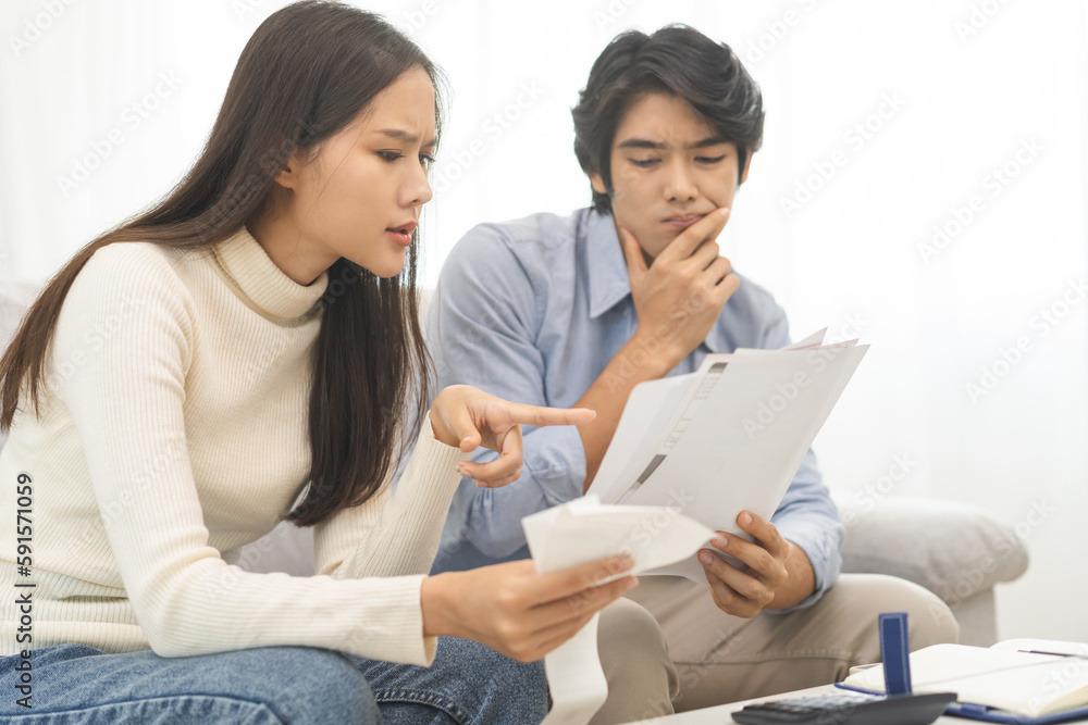 Stressed financial owe asian young couple love hand in holding bills, sitting on sofa together, stressed and confused by calculate expense, mortgage or loan. Debt, bankrupt or bankruptcy people. Stressed financial owe asian young couple love hand in holding bills, sitting on sofa together, stressed and confused by calculate expense, mortgage or loan. Debt, bankrupt or bankruptcy people.