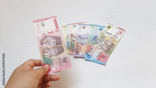 Hand holding showing indonesia rupiah, new rupiah money series banknotes for buying, selling, isolated on white background