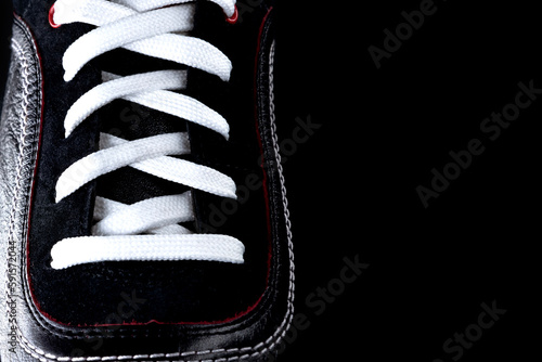 Men's sports shoes on a black background. White shoelaces. Empty space for an inscription