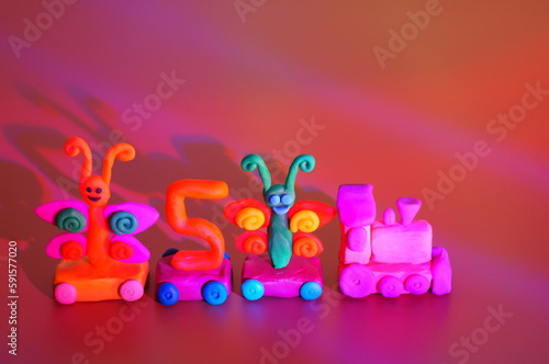Toy train made of plasticine with butterflies and the number 5. Birthday. A festive event. Color background. © Станислав 