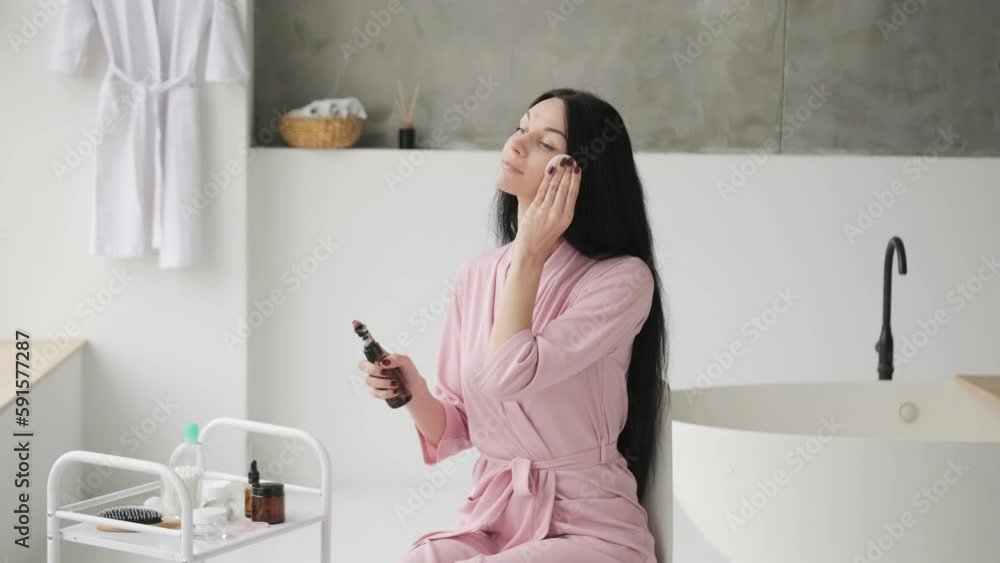 Beautiful brunette woman removing makeup from her face. Taking good care of her face. Beautiful young woman cleaning her face with sponge and smiling Beautiful brunette woman removing makeup from her face. Taking good care of her face. Beautiful young woman cleaning her face with sponge and smiling