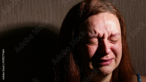 Woman hysterically cry in dark room closeup. Tears rolling down cheeks. Splash out emotions, weep bitterly. Emotional breakdown, mental health problems. Depression and hysteria concept.
