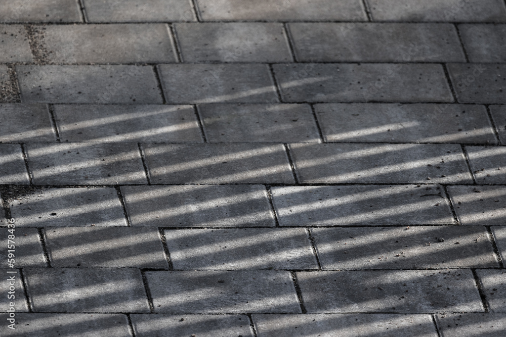 Gray concrete cobble road with striped shadows pattern Gray concrete cobble road with striped shadows pattern