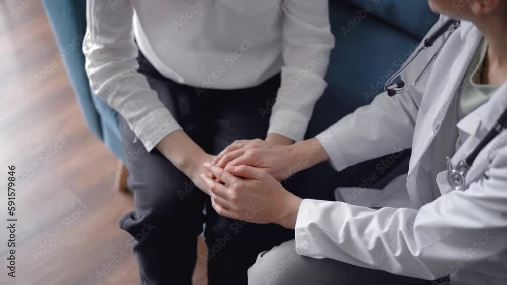 Doctor reassuring patient while sitting and discussing something near each other on a blue sofa. Empathy in medicine concept Doctor reassuring patient while sitting and discussing something near each other on a blue sofa. Empathy in medicine concept