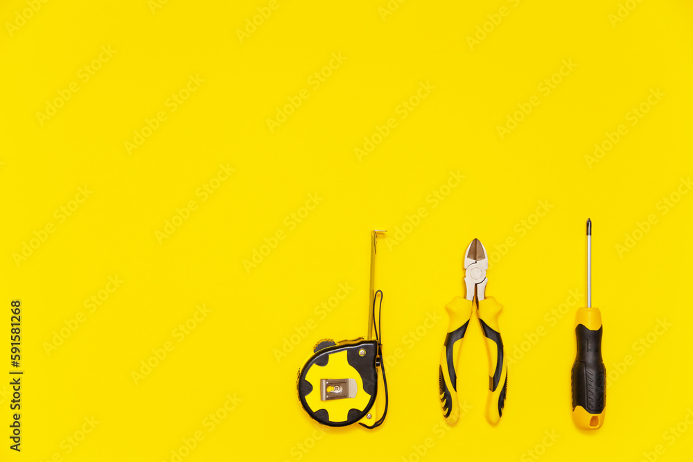 Set of bench tools, screwdriver, cutting pliers and tape measure on yellow background, flat lay Set of bench tools, screwdriver, cutting pliers and tape measure on yellow background, flat lay