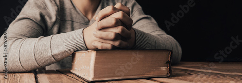 man praying with hands crossed and Holy Bible