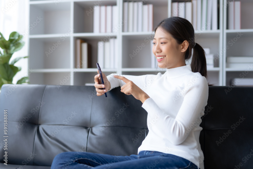 Beautiful young smiling Asian woman using smartphone on sofa at home. Beautiful young smiling Asian woman using smartphone on sofa at home.