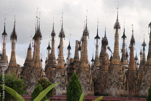 Estupas o pagodas de piedra tallada con la punta llena de ornamentación con campanas colgando en Kakku, Birmania, Myanmar, y un cielo blanco con nubes
