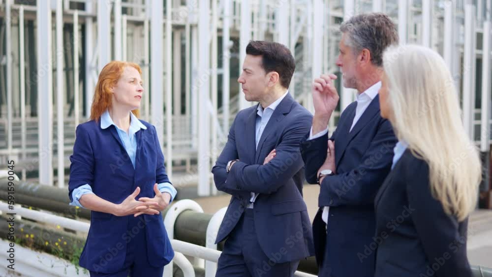 Redhead businesswoman talking with a group of business people outdoors Redhead businesswoman talking with a group of business people outdoors