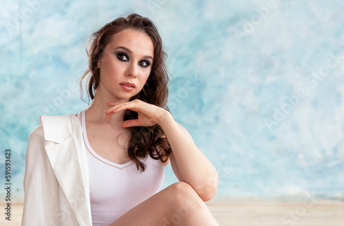 professional ballerina in a white gymnastic leotard is dancing in a room with blue walls