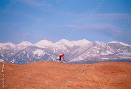 Man Cycling over Landscape near Mountains Moab, Utah, USA photo