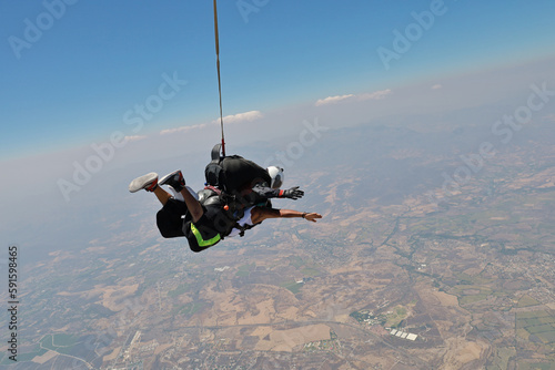 Skydiving. Tandem is falling above the summer land.