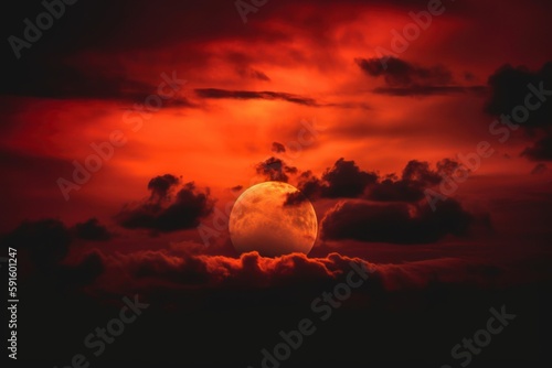 red sun with clouds behind on the dark sky, a red sun with clouds in the background