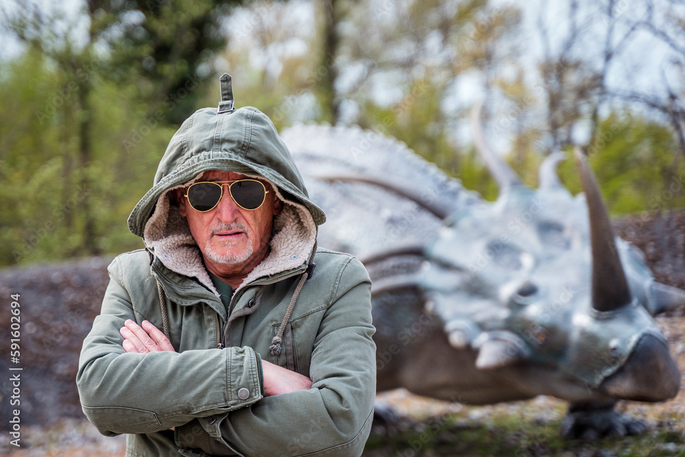 portrait of expressive middle aged man posing in front of dinosaur models in a park