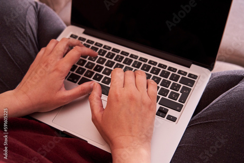 Close-up of a woman using a laptop on her legs