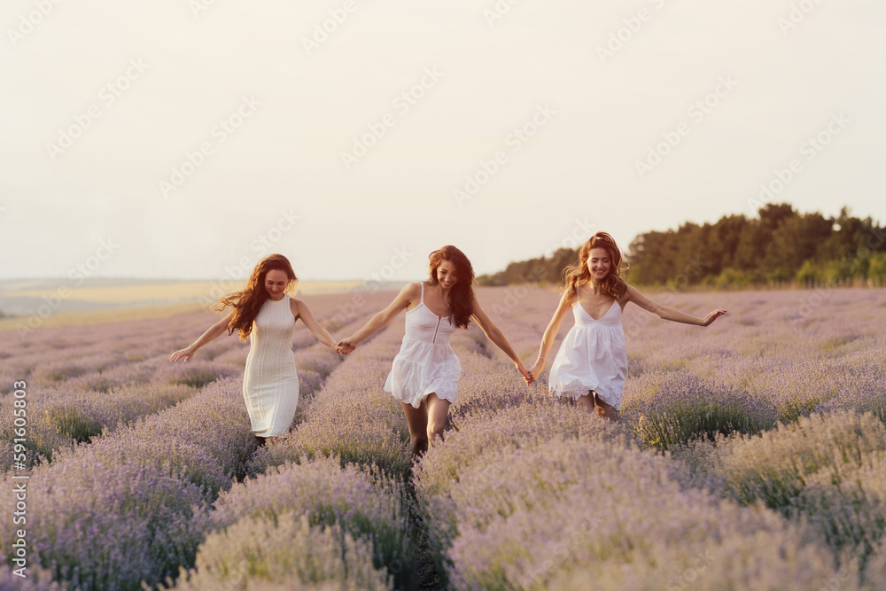 Pretty, happy, young girls in white dresses running at the lavender field. Happy moments.