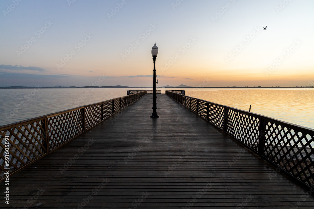 wooden pier over lagoon during sunrise 