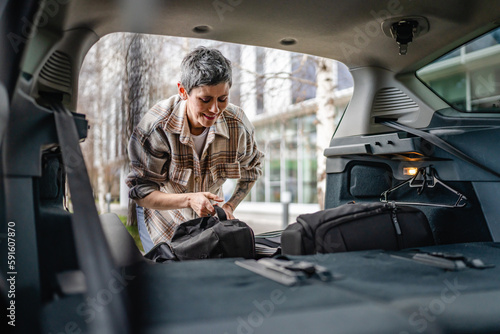 one senior woman pack luggage baggage suitcase in the trunk of the car