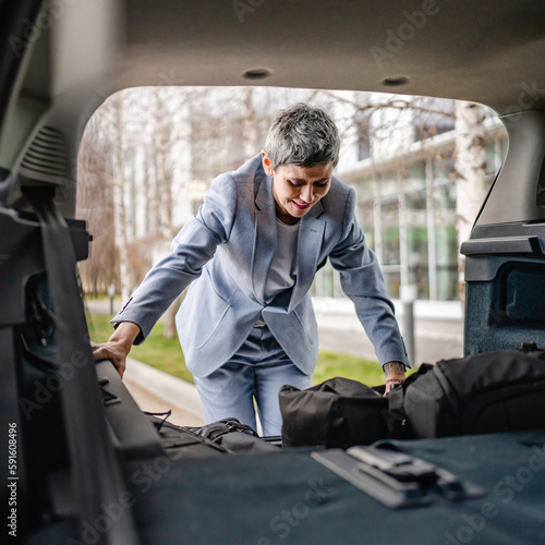 one senior woman pack luggage baggage suitcase in the trunk of the car