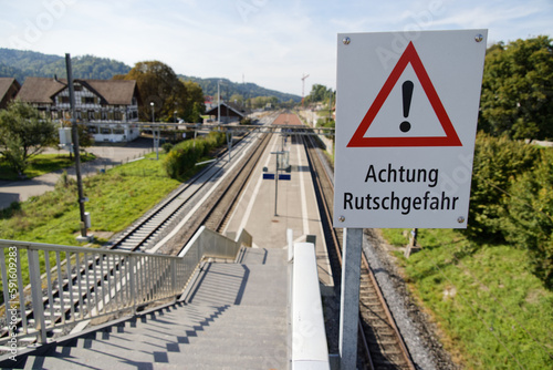 caution danger of slipping sign in front of a railroad station staircase german text translation: caution danger of slipping!