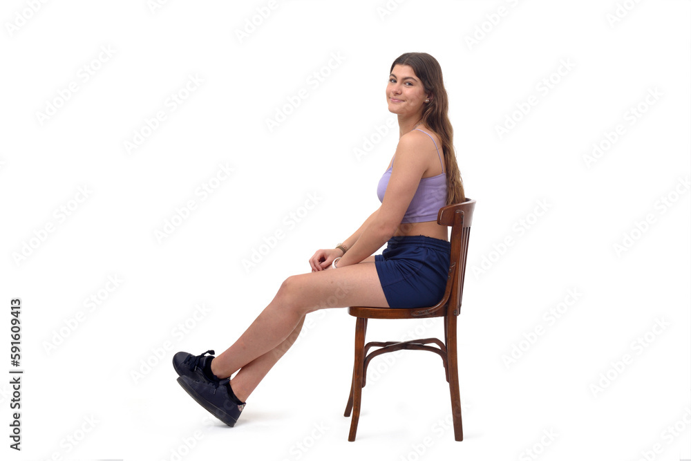 side view of a young girl sitting on chair with Stretched legs and looking at camera on white background side view of a young girl sitting on chair with Stretched legs and looking at camera on white background