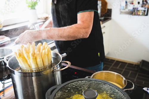 old man cooking asparagus in the kitchen