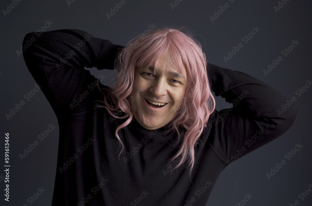 Portrait of a man in a pink wig, looking at the camera, grimacing, posing.