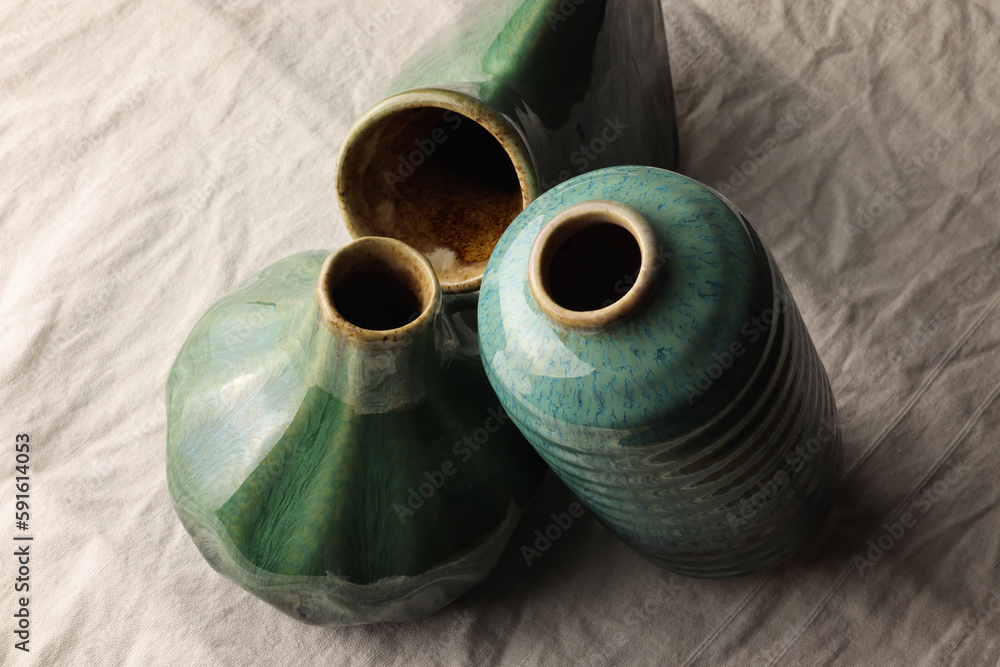 Vasi in ceramica di colore verde, blu e azzurro, composizione vista dall’alto su un fondo di tela di lino
