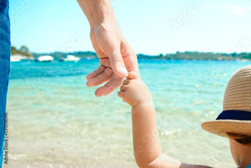 A Hands of a happy parent and child in nature by the sea on a journey background