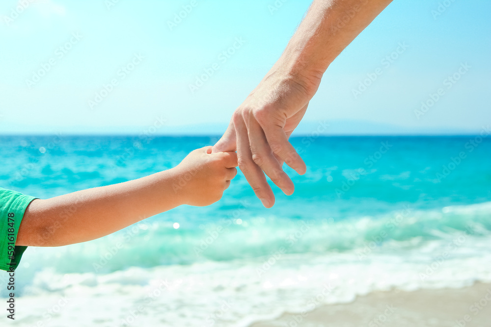 A Hands of a happy parent and child on the seashore on a journey trip in nature A Hands of a happy parent and child on the seashore on a journey trip in nature