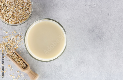 A glass of oat milk and oatmeal on gray background. Top view. The concept of alternative lactose-free dairy products.