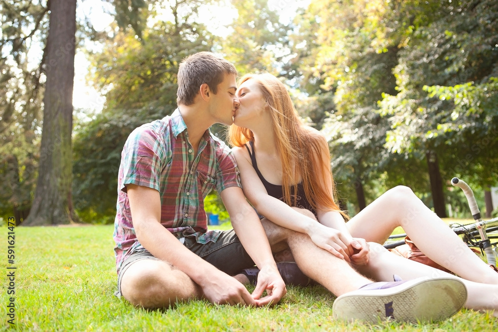 Young Couple Sitting on the Ground and Kissing in Park on a Summer Day, Portland, Oregon, USA Young Couple Sitting on the Ground and Kissing in Park on a Summer Day, Portland, Oregon, USA