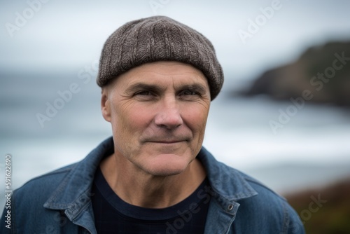 Medium shot portrait photography of a satisfied, man in his 50s wearing a warm beanie or knit hat against a beach background. Generative AI