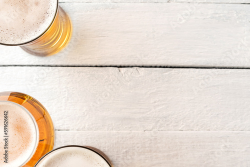 Overhead shot of beer mugs on white wooden background with copyspace. Close up