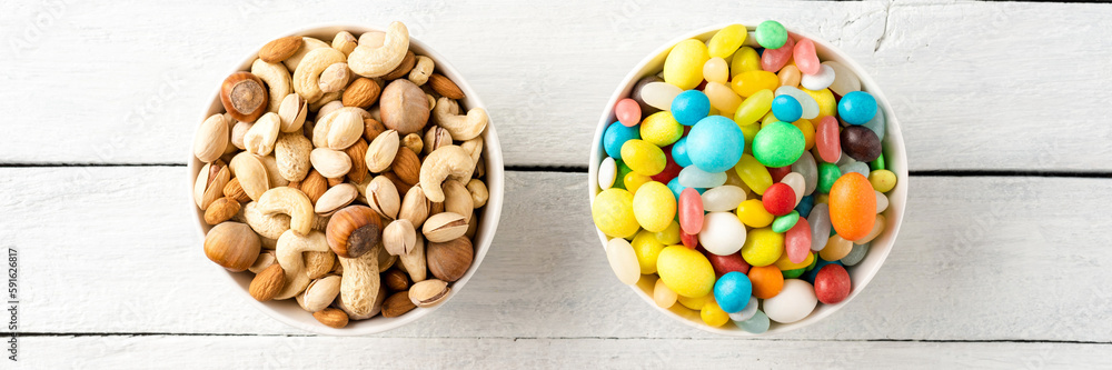 Diet decision concept. Mixed nuts and sweet in bowls on white wooden background. Top view Diet decision concept. Mixed nuts and sweet in bowls on white wooden background. Top view