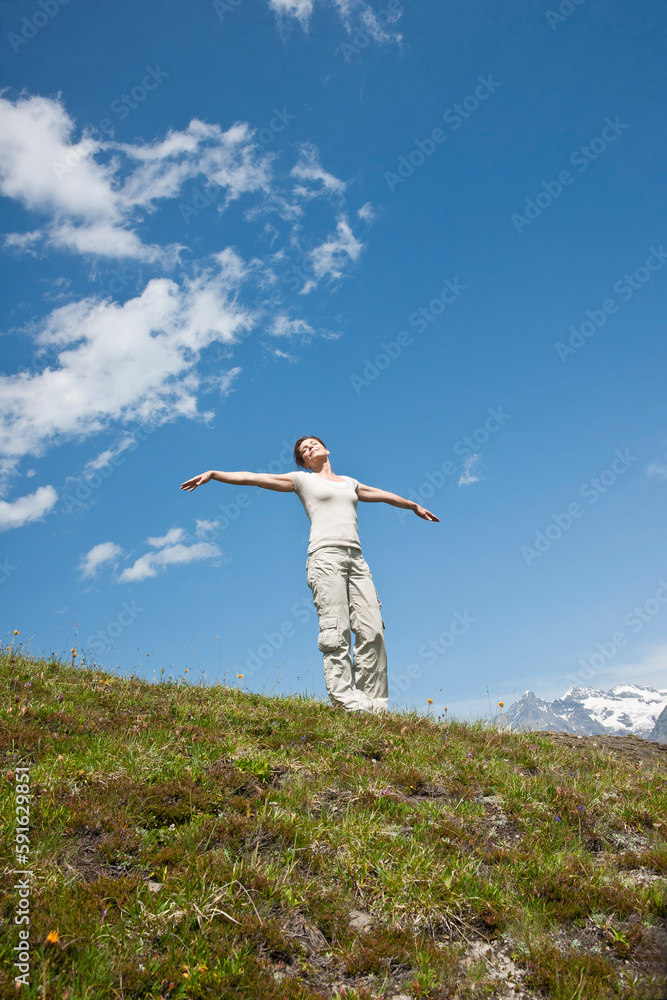 Woman Standing on Mountain Side with Arms Outstretched, Bernese Oberland, Switzerland