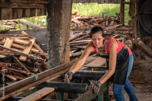 Portrait of a woman looking to the side with worried face, working in a sawmill.